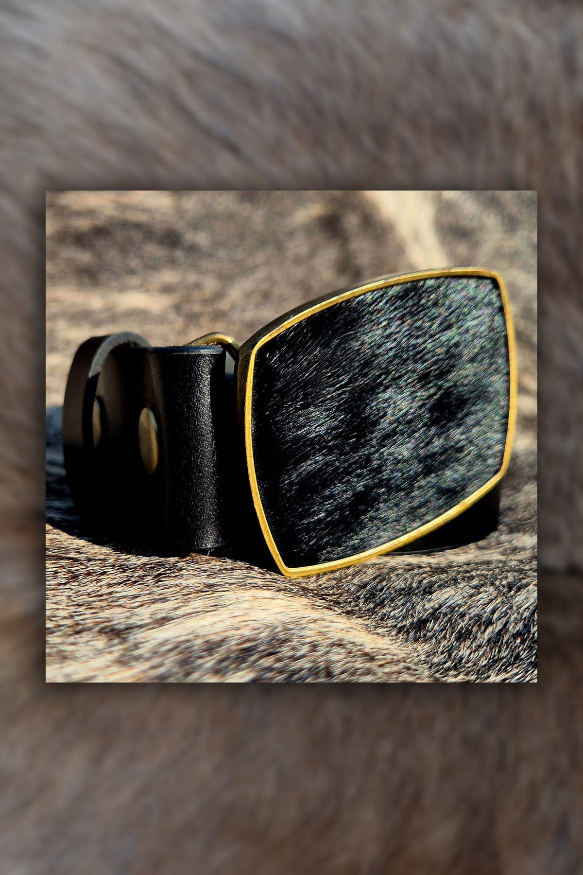 Black leather belt with a large rectangular buckle on a textured brown background