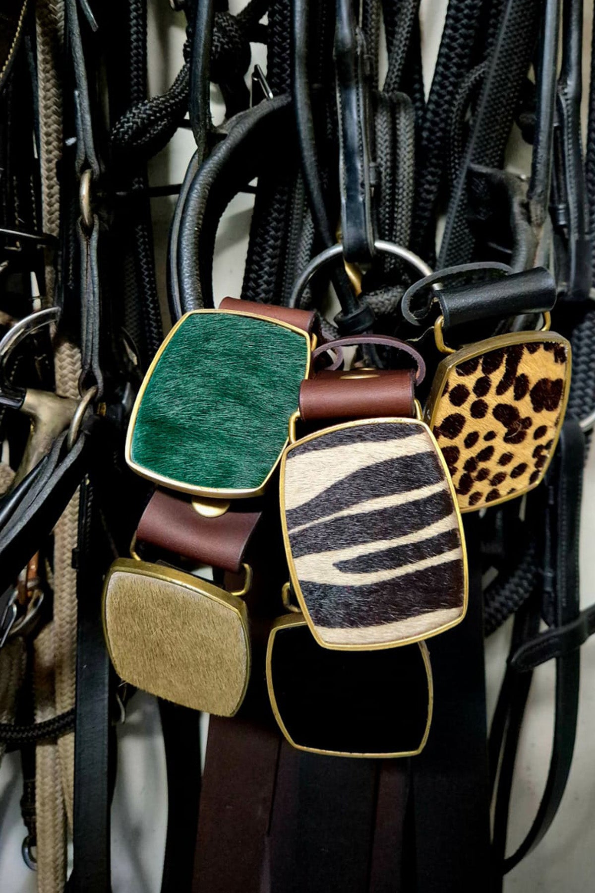 Collection of colorful leather belts with various patterns on a dark background