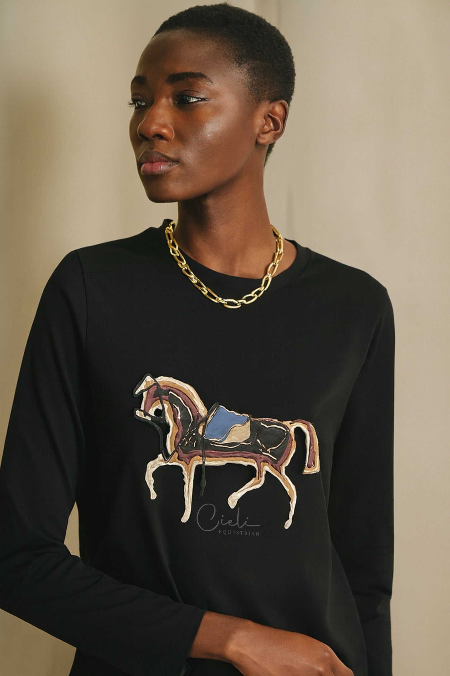 Person wearing a black sweater with a horse graphic and 'Cieli' branding.