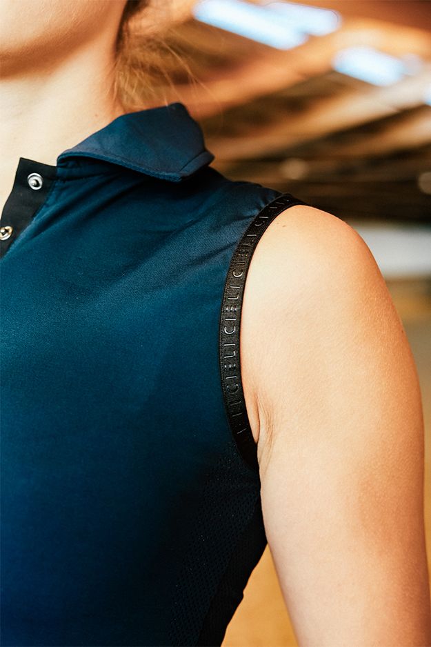 Person wearing a blue sleeveless top with a blurred background