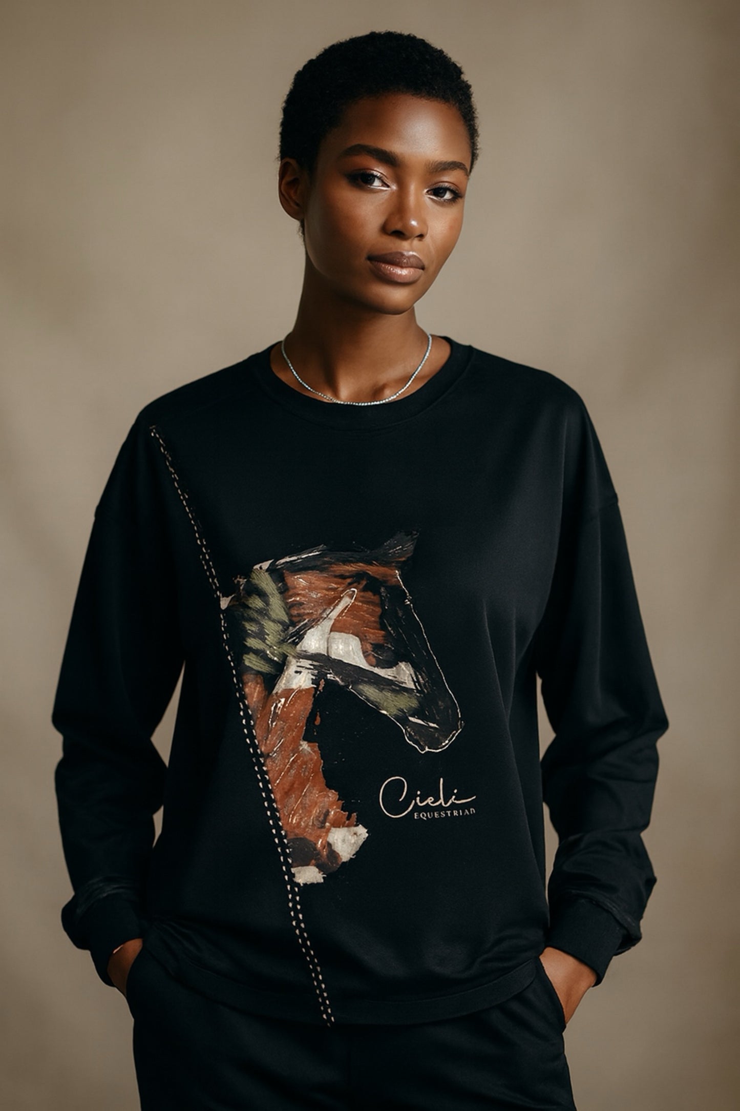 Person wearing a black sweatshirt with a horse graphic and 'Cieli' branding on a beige background