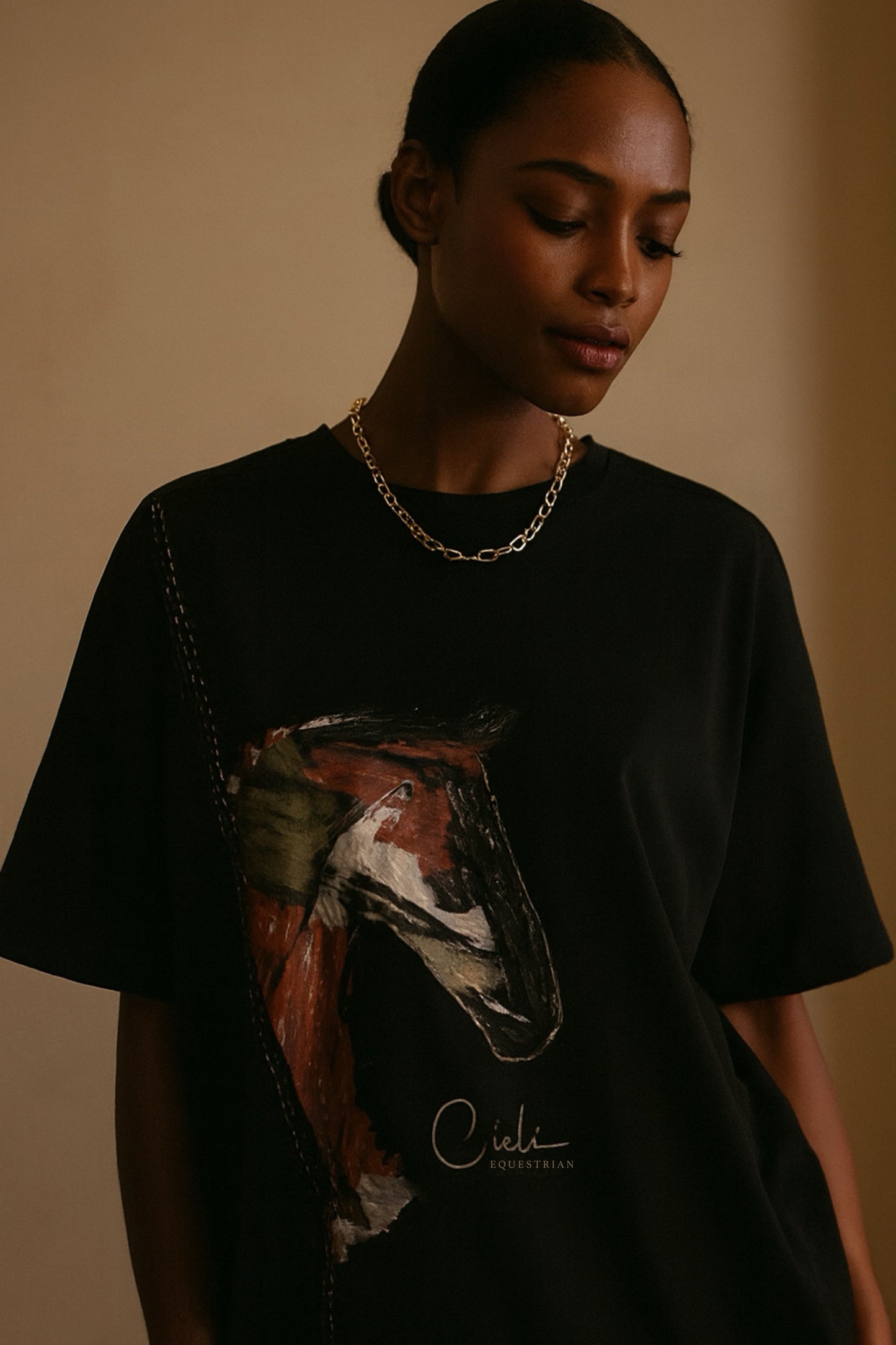 Person wearing a black t-shirt with a horse graphic and 'Cieli' branding on a beige background