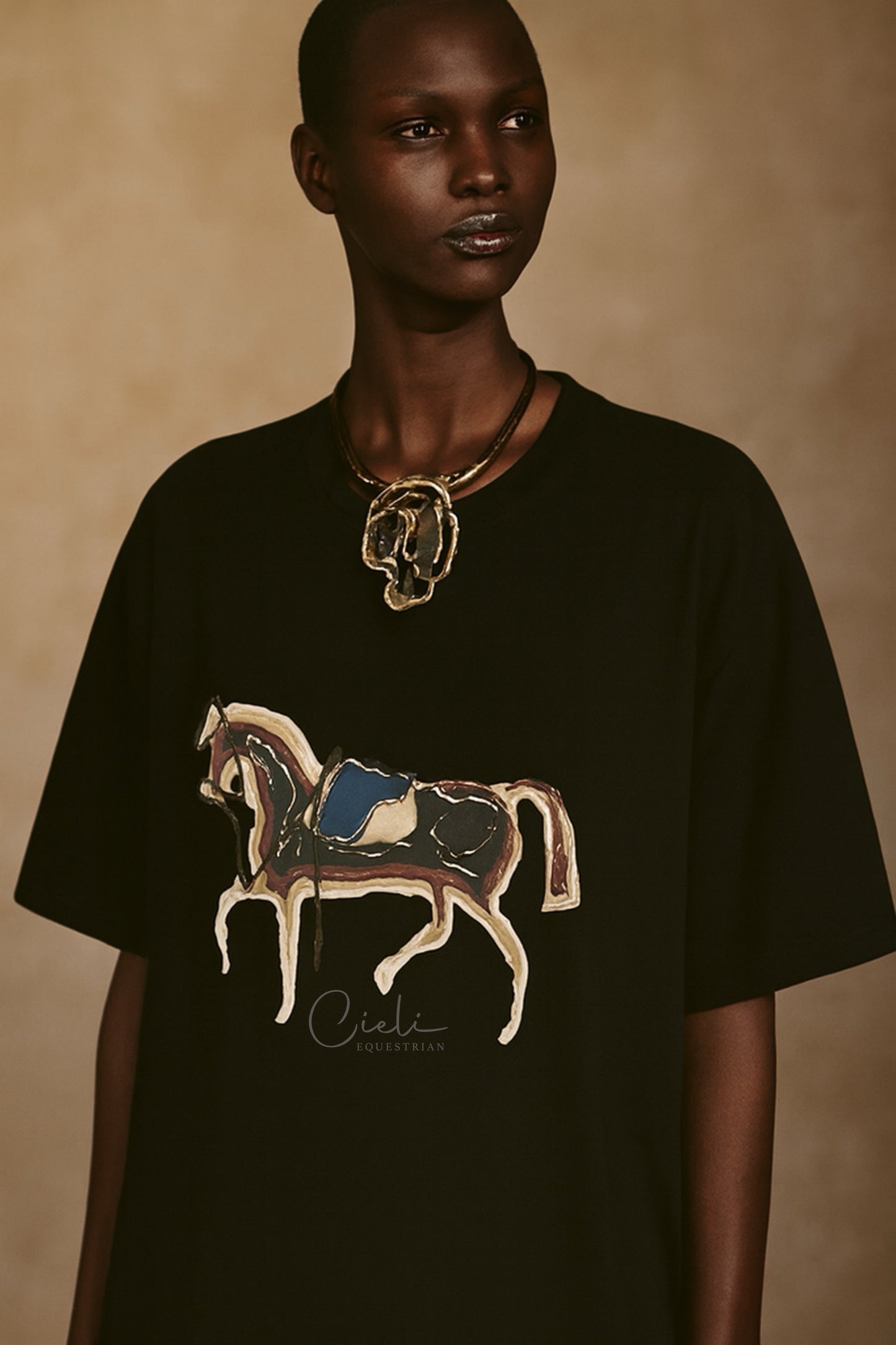Person wearing a black t-shirt with a horse design on a beige background