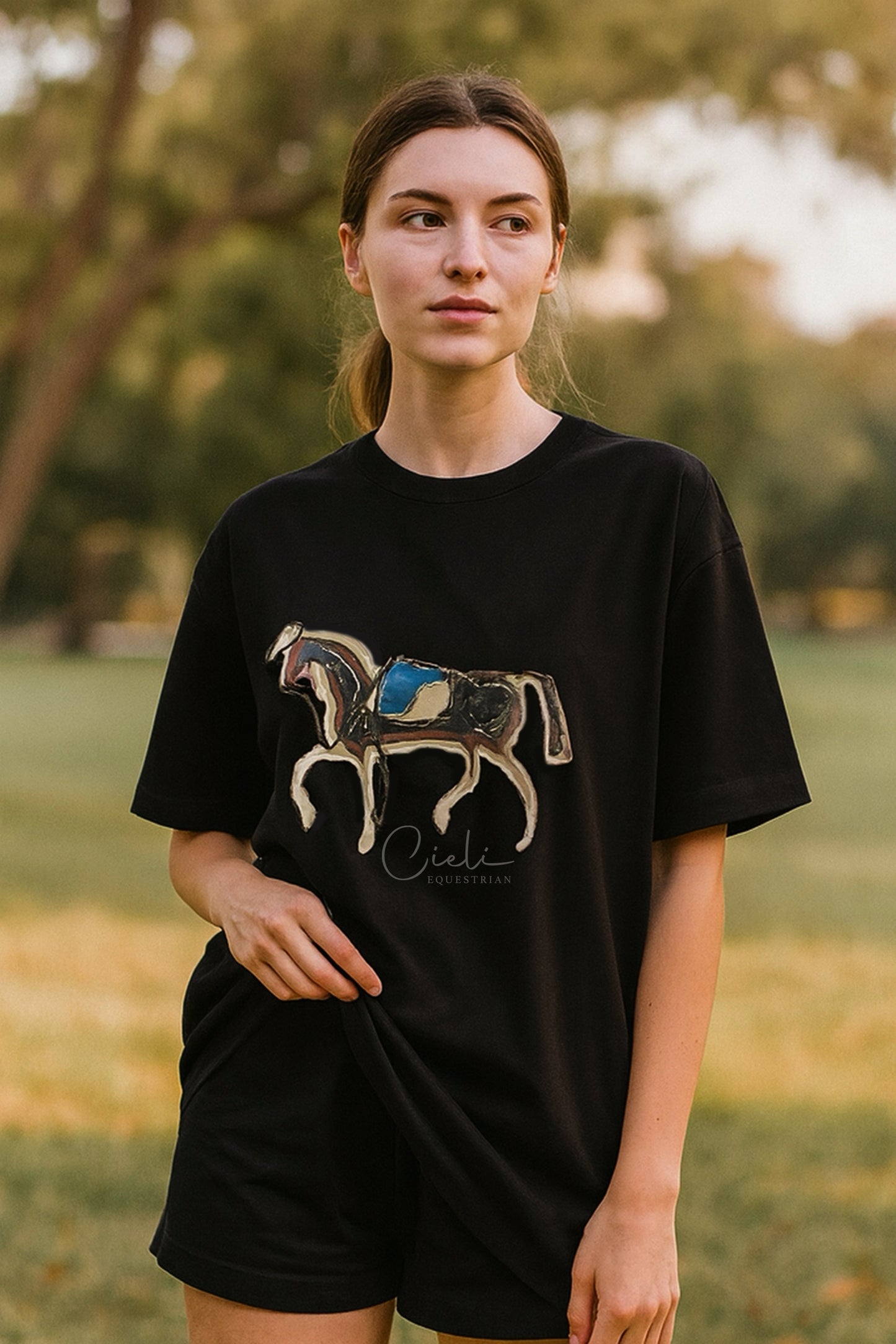 Person wearing a black t-shirt with a horse graphic in an outdoor setting