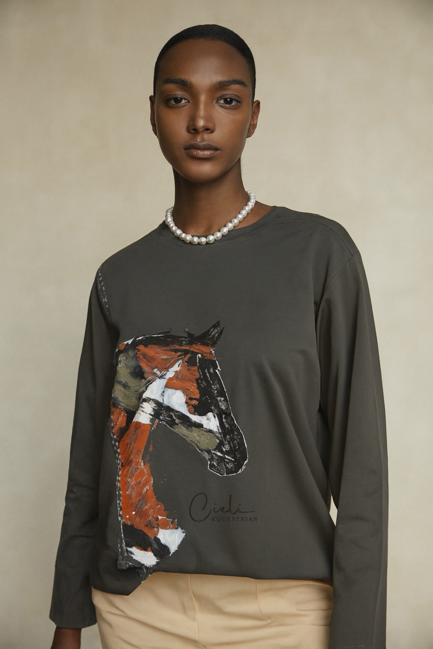 Person wearing a green long-sleeve shirt with a horse graphic on a beige background