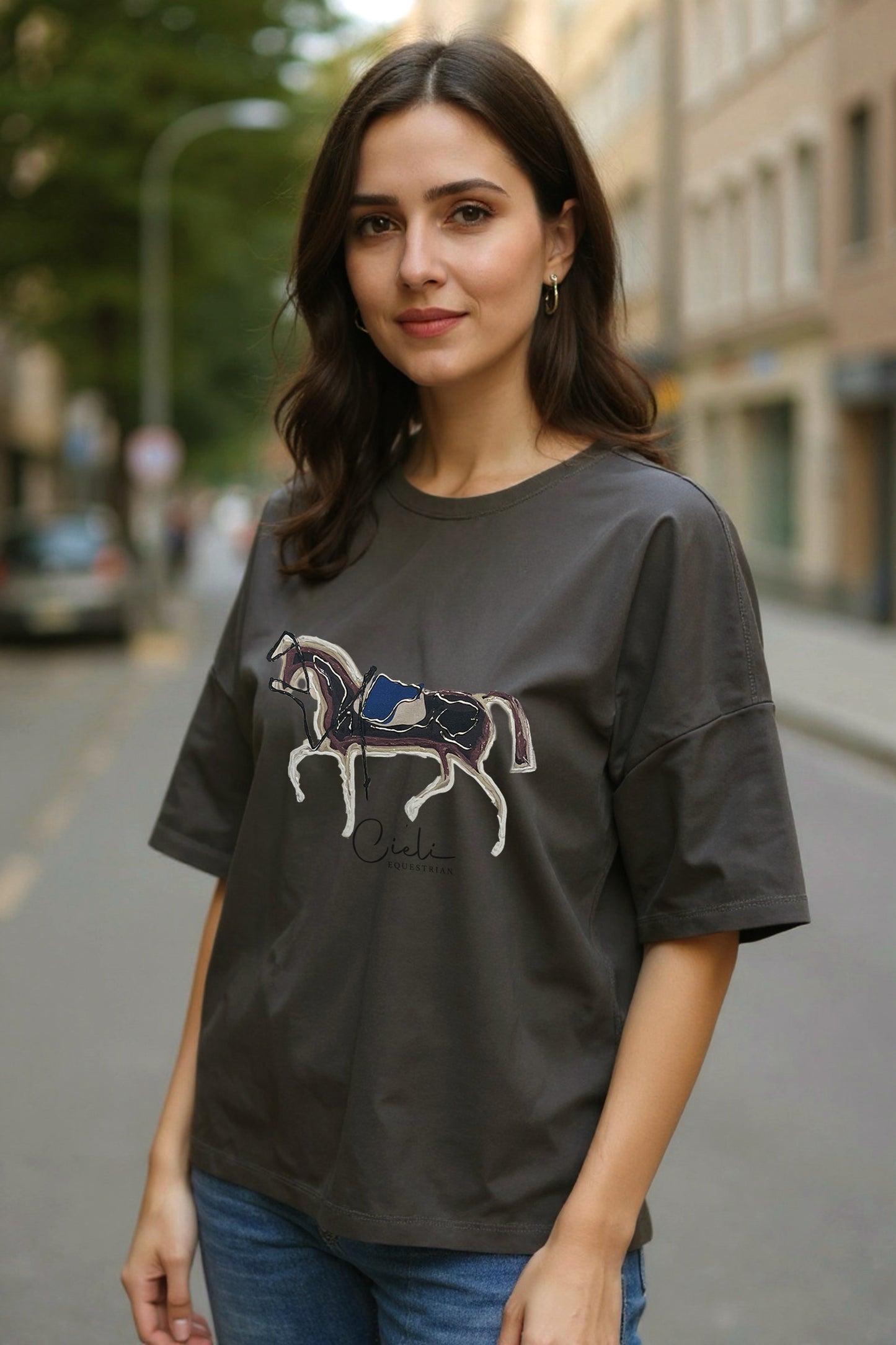 Woman wearing a green t-shirt with a horse graphic on a city street.