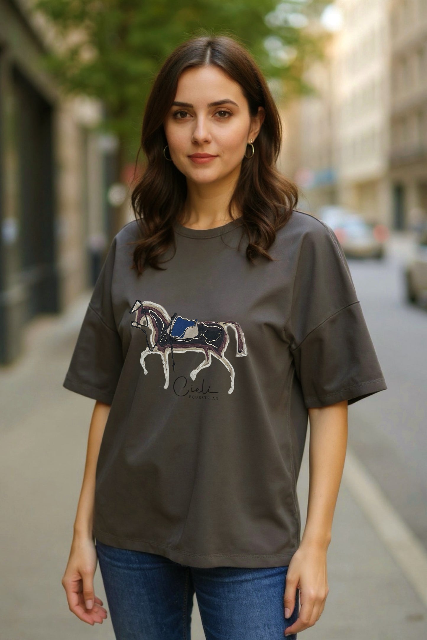 Woman wearing a green t-shirt with a horse graphic on a city street.