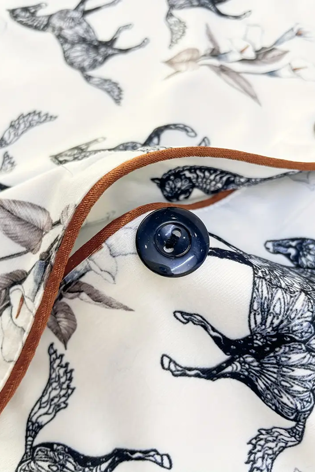 Product with black and white animal illustrations on a white background, featuring brown piping and button.