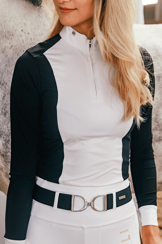 A person wearing a long sleeve show shirt in white and black colors, and pleats at the back. The shirt has a zipper at the neck and a belt around the waist.