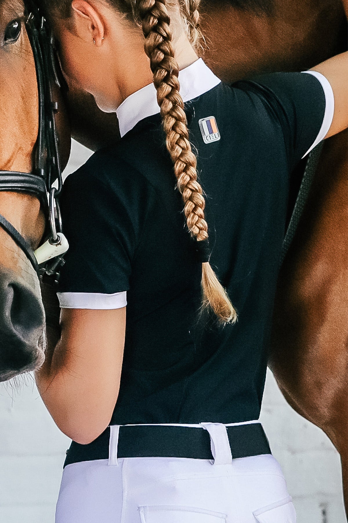 A person wearing a short sleeve show shirt in white with black accents, featuring a zipper at the neck and pleats at the back.