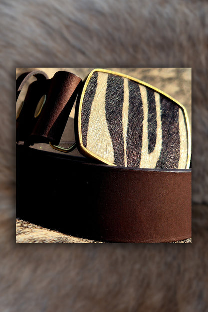 Brown leather belt with zebra pattern buckle on a fur background