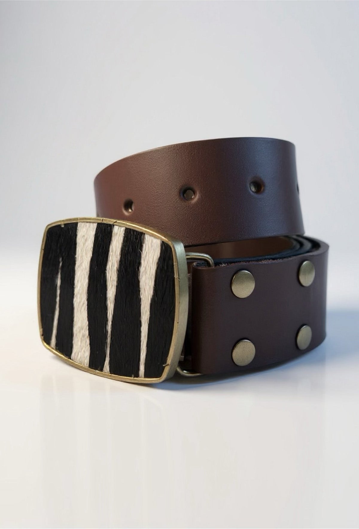 Brown leather belt with a zebra-striped buckle on a white background