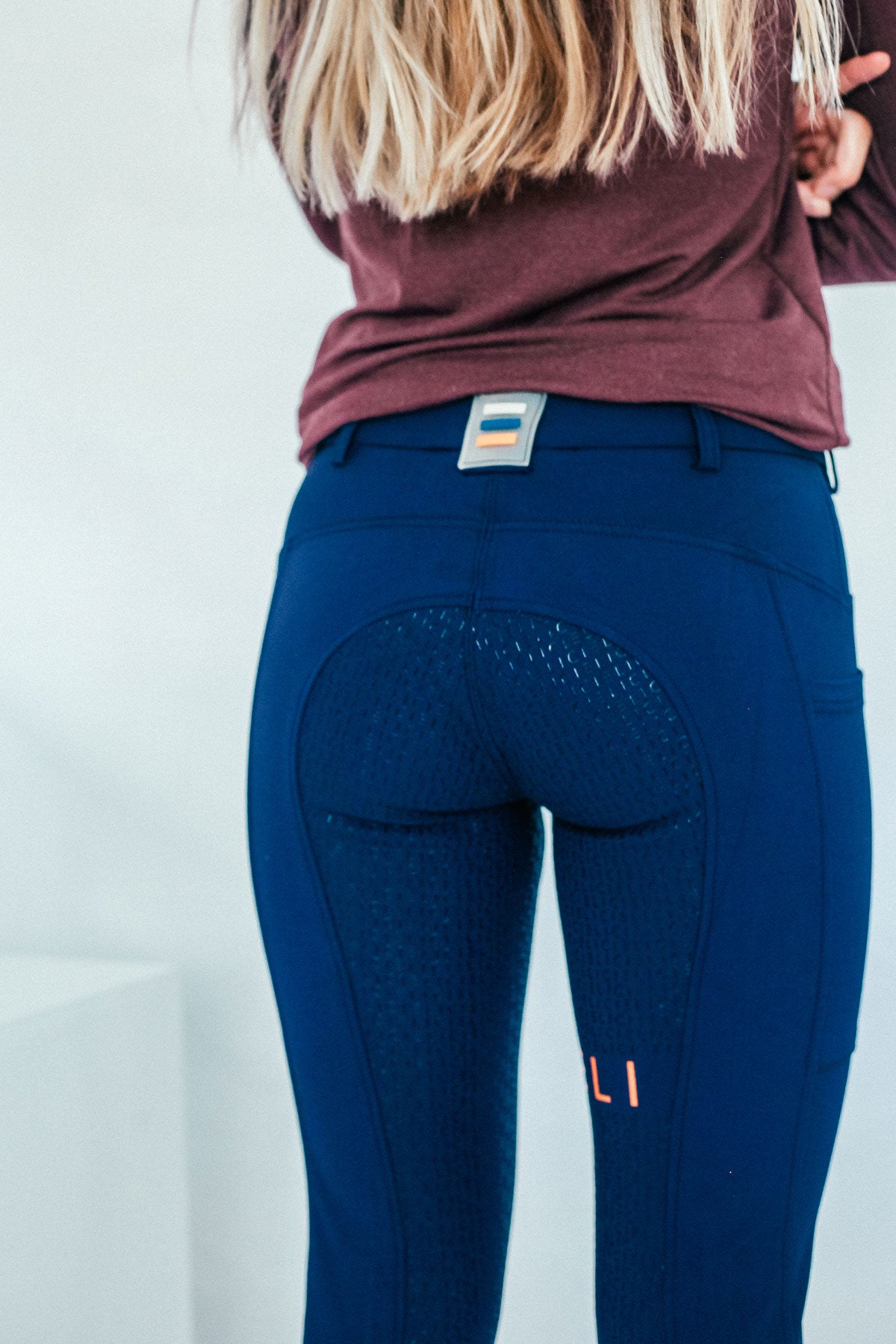 Lady wearing everyday navy equestrian pants, resembling a sporty twist on modern riding breeches with full grip.