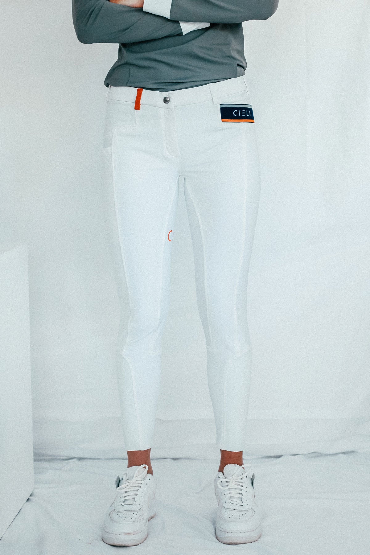 Lady wearing show performance white equestrian pants, resembling a sporty twist on modern riding breeches with full grip.