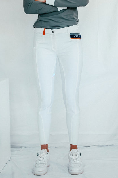 Lady wearing show performance white equestrian pants, resembling a sporty twist on modern riding breeches with full grip.