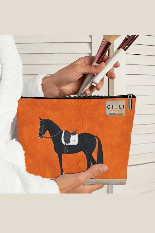 Orange pouch with horse design held by a person, featuring the brand 'Cieli'.