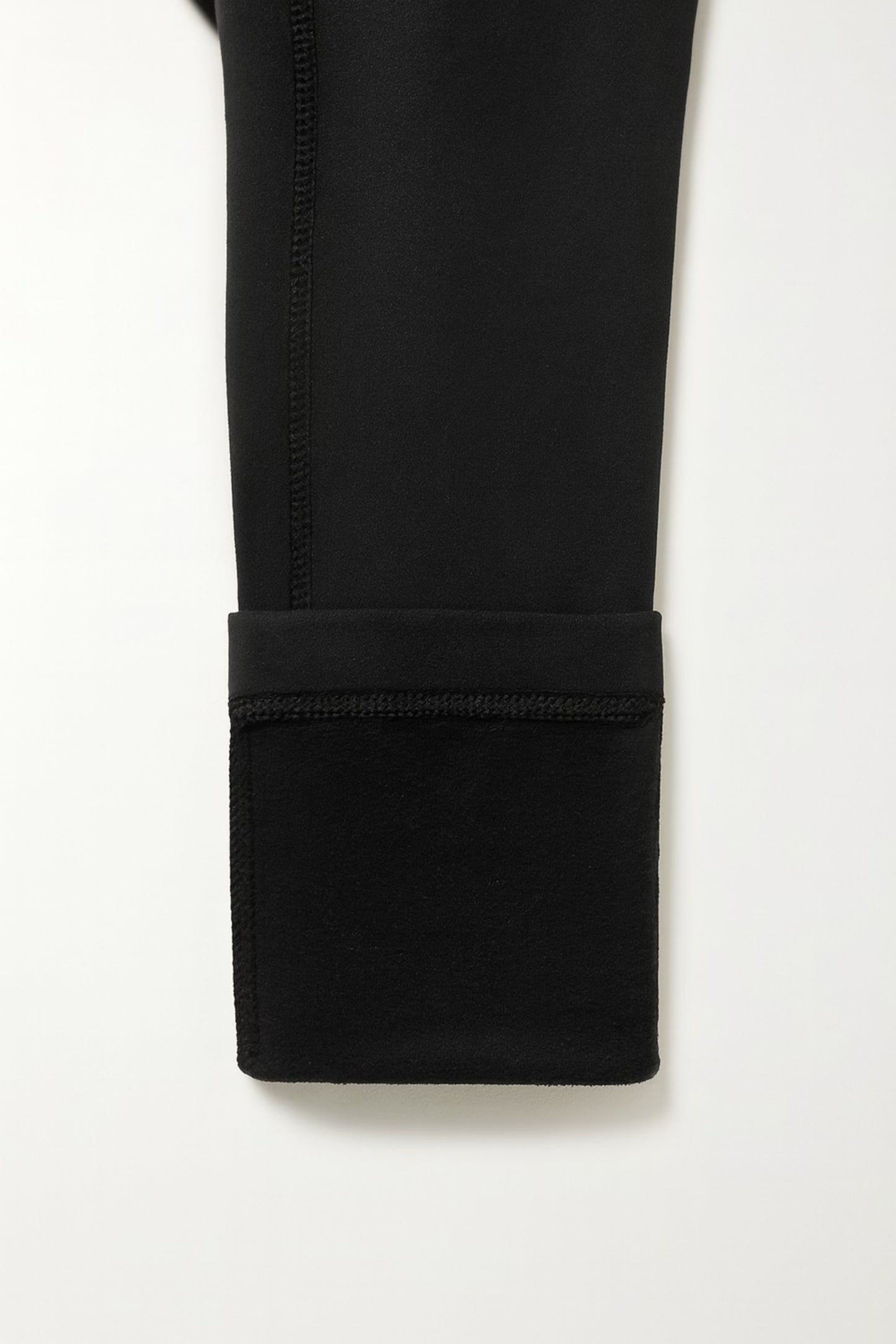 Close-up of a black pants folded up with a white background