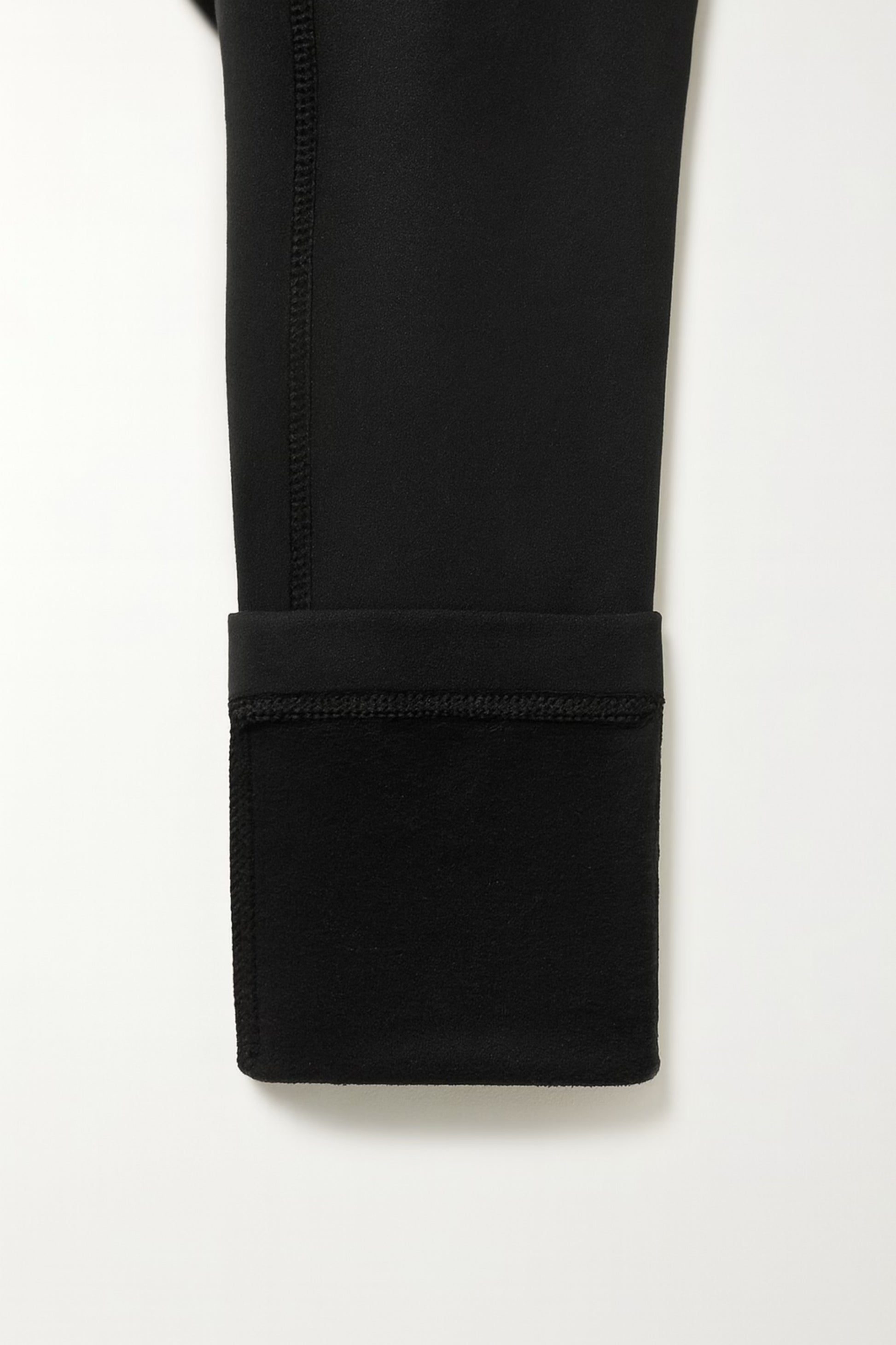 Close-up of a black pants folded up with a white background