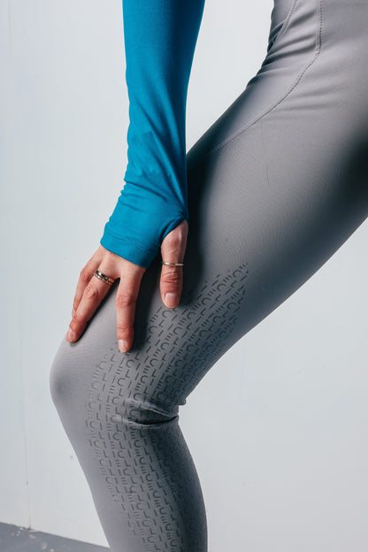 Person wearing gray riding leggings with a  on a light gray background