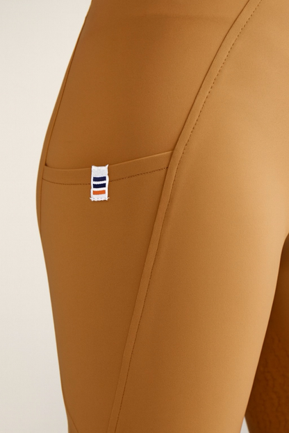 Close-up of brown breeches with a brand label on a beige background