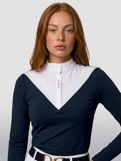 A woman wearing a navy long-sleeve athletic top with a contrasting white V-neck collar panel and gold 'CELI' branding on the chest, paired with a white belt.