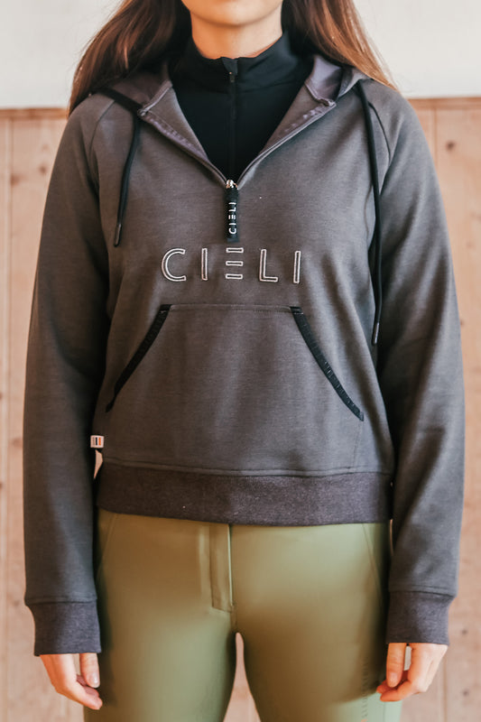 Dark haired girl wearing a dark grey hoodie with Cieli embroidery and custom ribbed elastic and zip puller