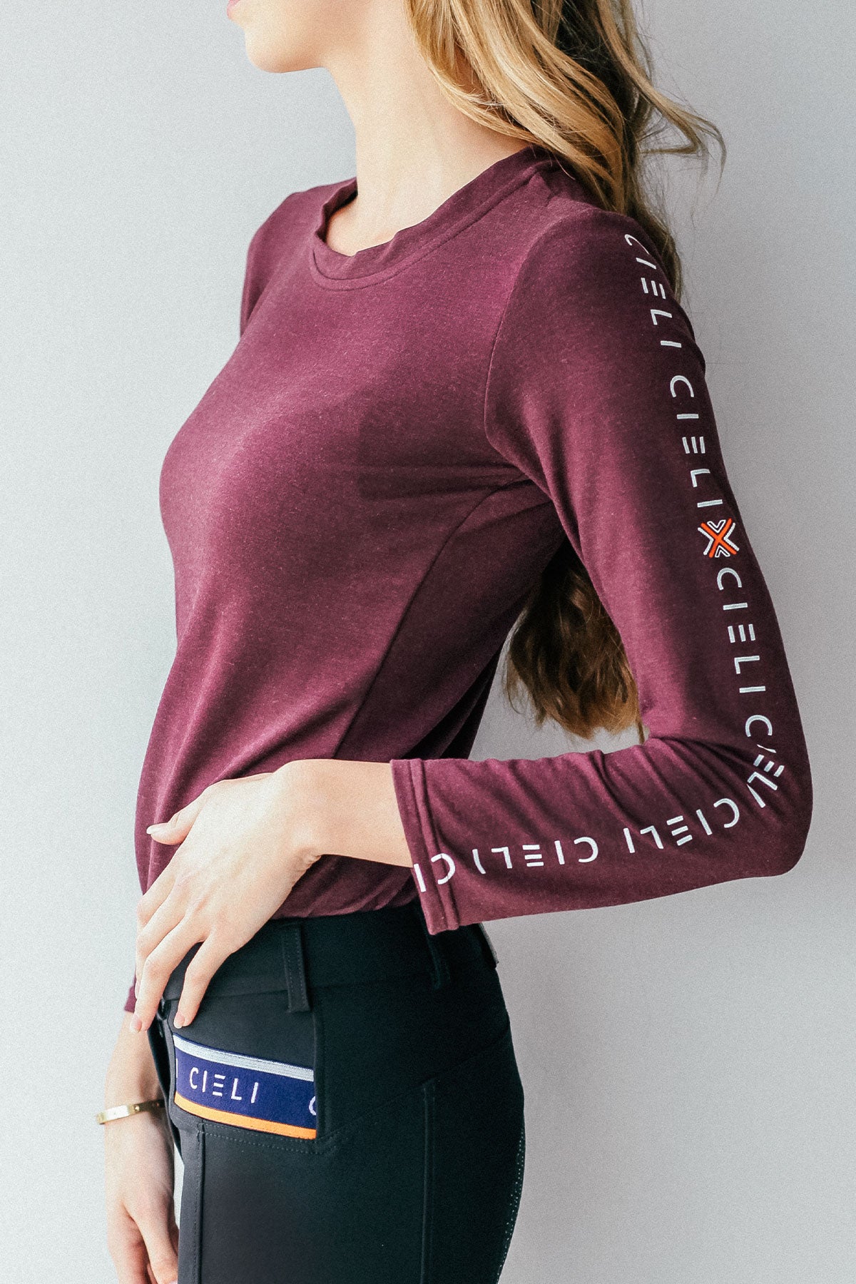 Lady wearing a Cieli Equestrian long sleeve horse riding shirt in maroon with ultra soft fabric.