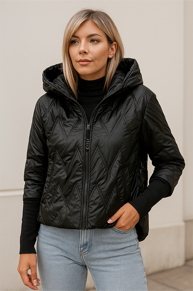 Woman wearing a black quilted jacket with a hood against a neutral background