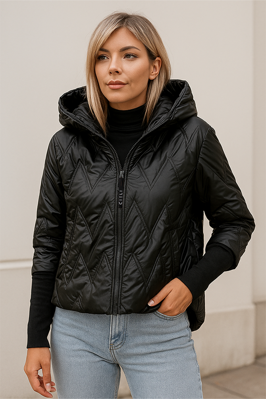 Woman wearing a black quilted jacket with a hood against a neutral background