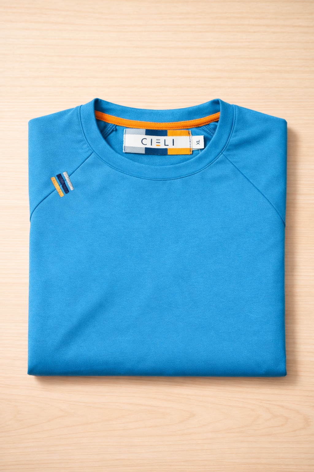 Folded blue long sleeve short with a brand label on a wooden surface