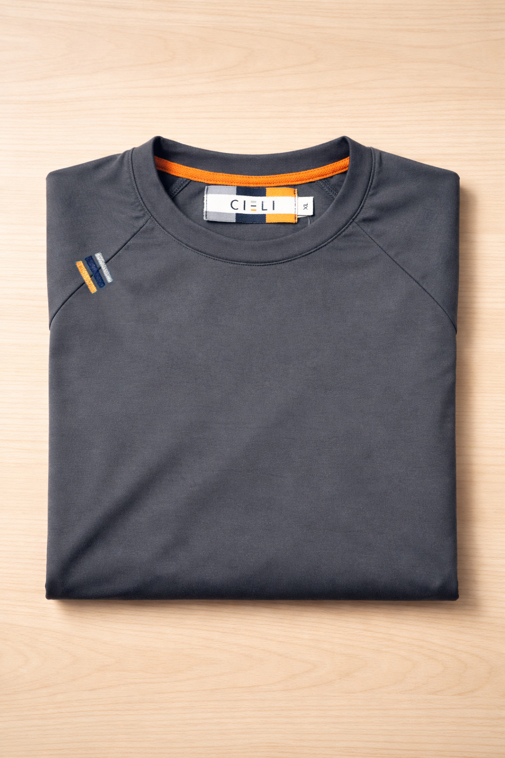 Folded dark gray long sleeve shirt with visible brand label on a light wooden surface