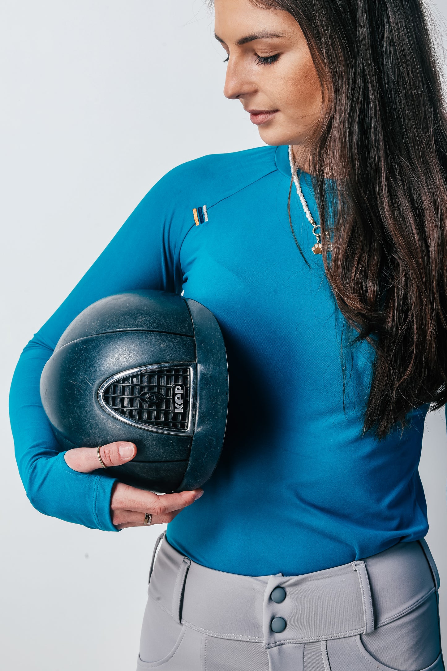 Person wearing a blue shirt holding a black helmet against a white background