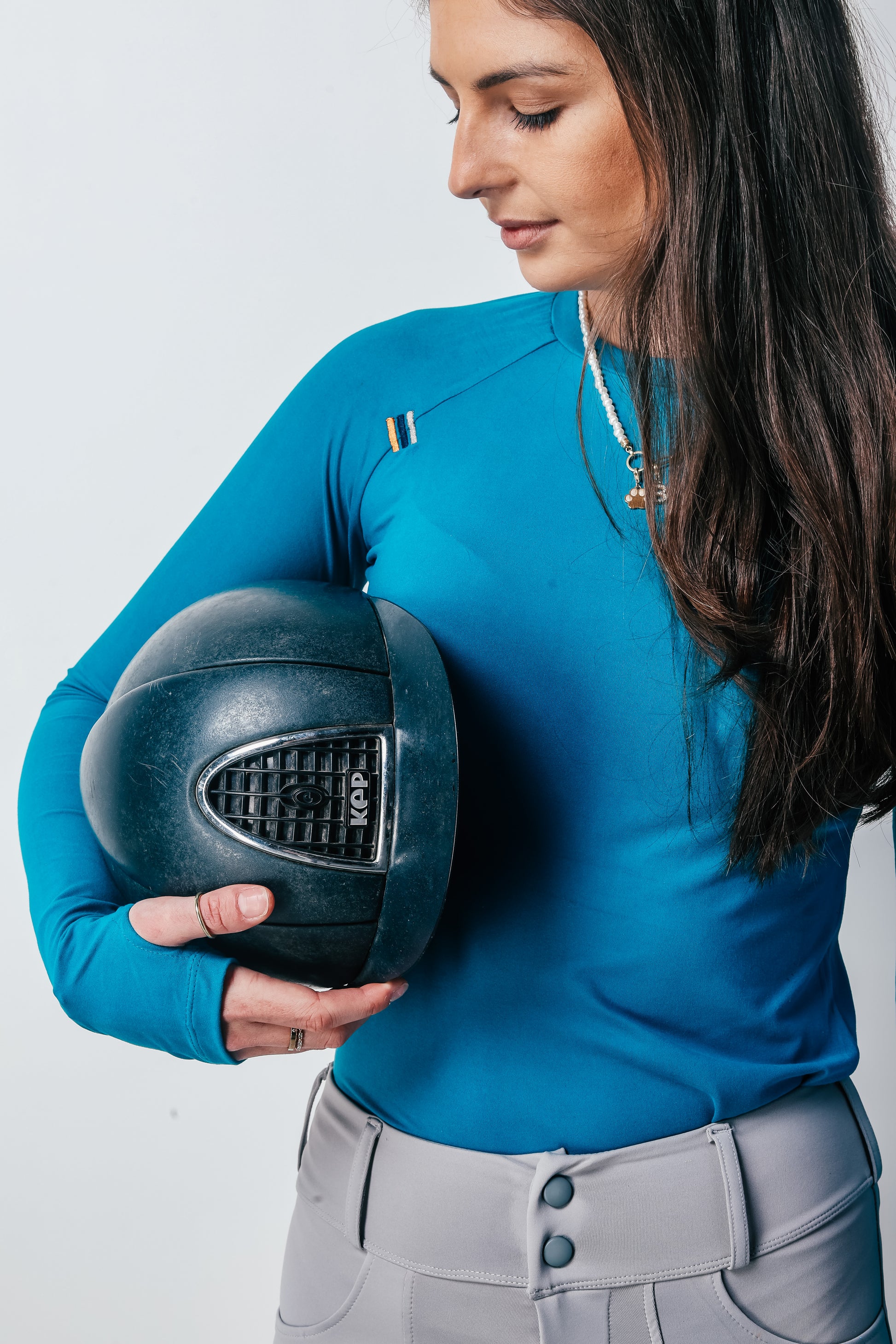 Person wearing a blue shirt holding a black helmet against a white background