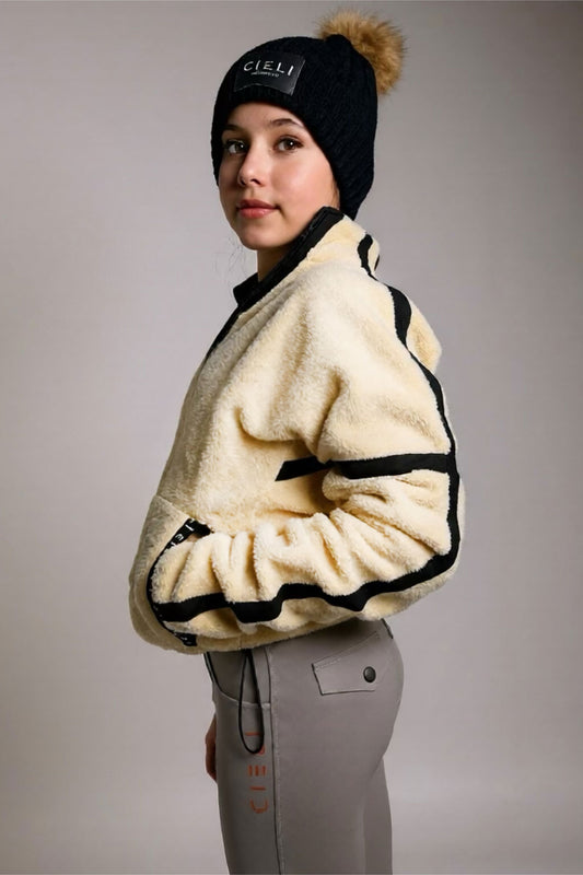 Person wearing a cream-colored fleece jacket with black accents, standing against a plain background.