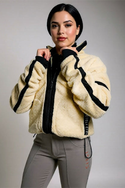 Woman wearing a cream-colored fleece jacket with black accents on a gray background
