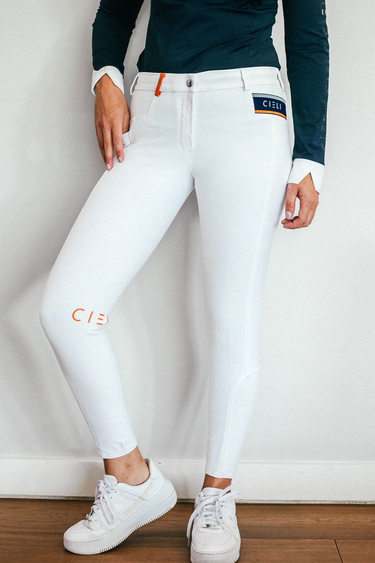 Lady wearing show performance white equestrian pants, resembling a sporty twist on modern riding breeches.