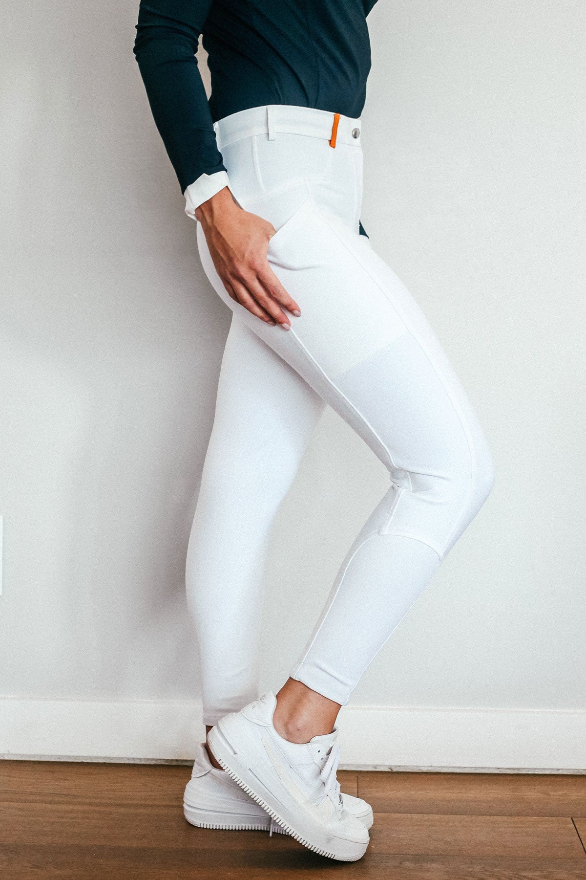 Lady wearing show performance white equestrian pants, resembling a sporty twist on modern riding breeches.